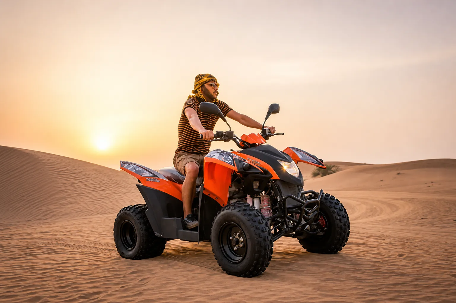 Two helmeted riders on quad bikes roaring over a dune ridge while the guide cheers