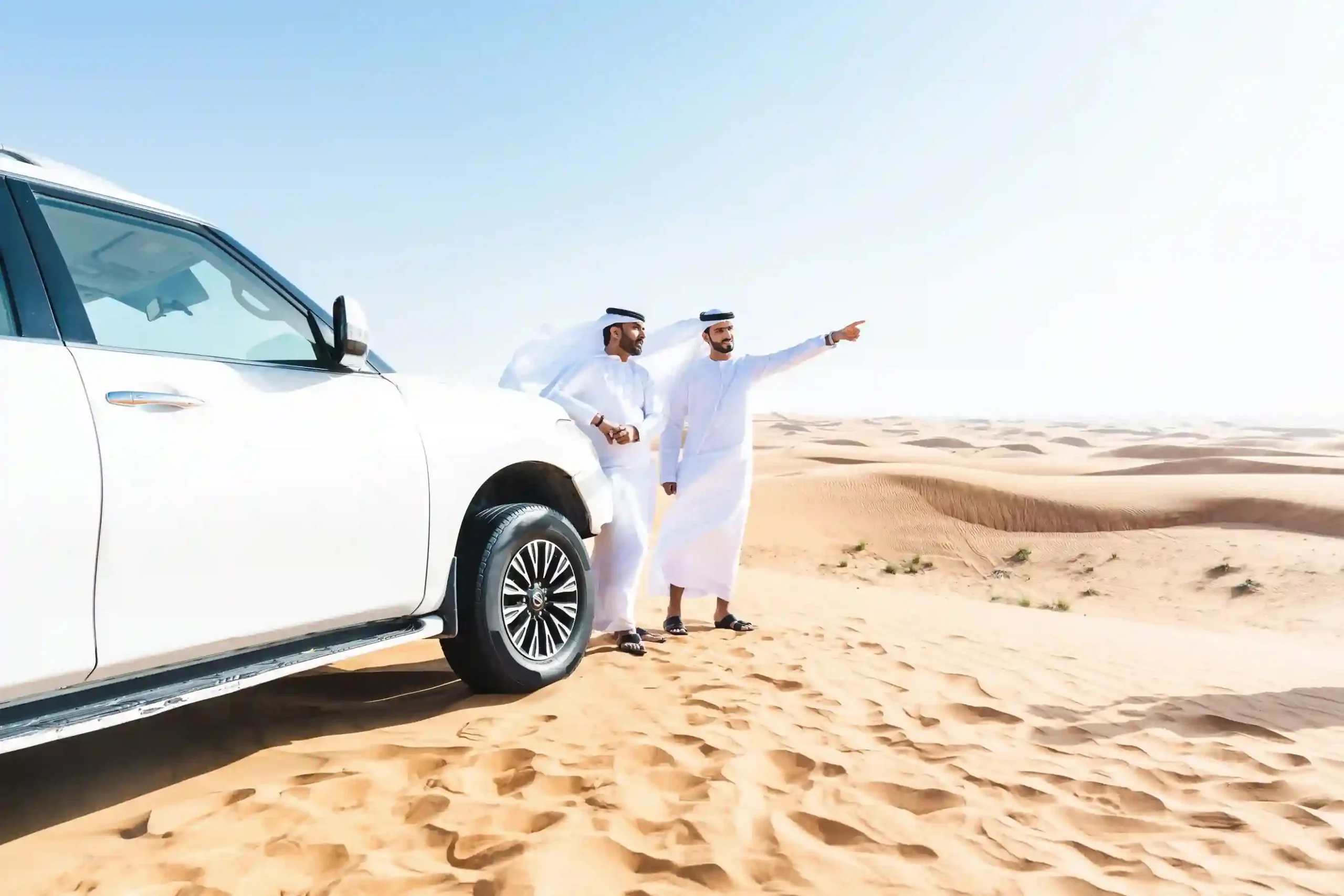 two emirate men in abu dhabi desert safari standing next to a land cruisers in the desert and going for a desert safari with self drive in abu dhabi